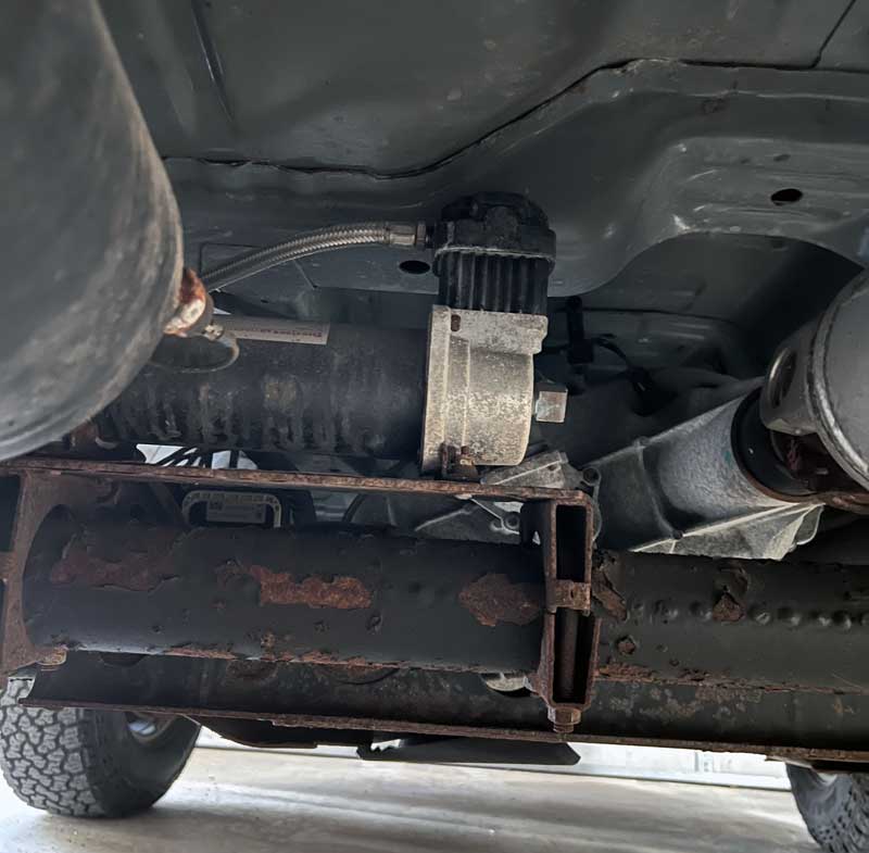 Firestone Air Compressor Mounted On Top Of A Crossmember Under The Truck