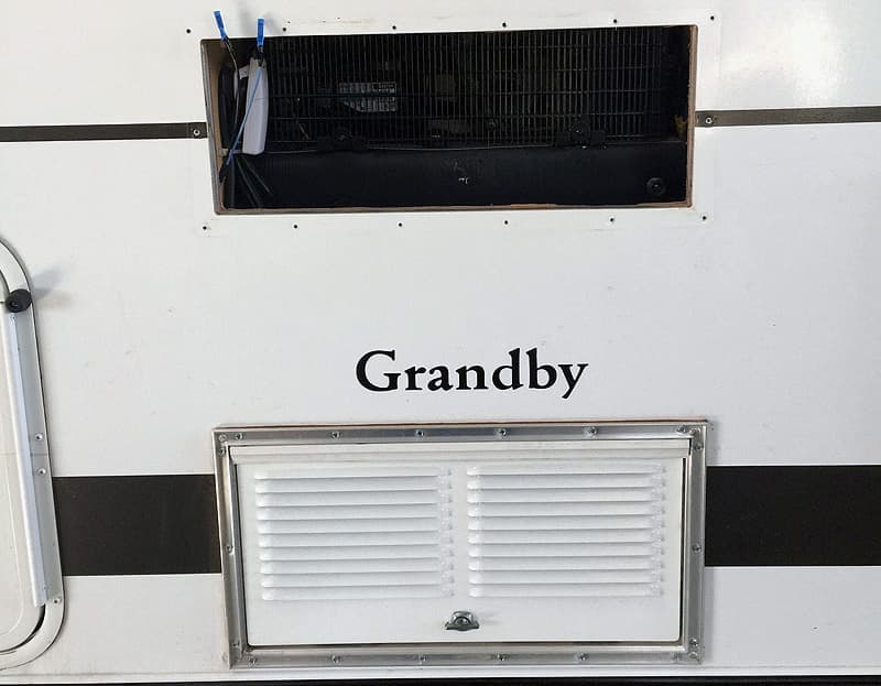 outside view of the camper with the venting removed to show the top fridge compartment