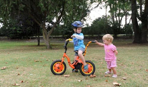 Youri riding his bike without training wheels and Michelle walking